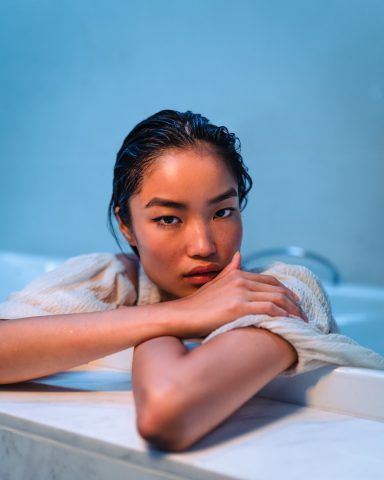 Young woman with wet hair resting at the edge of a serene spa pool, embracing a moment of calm and self-care.